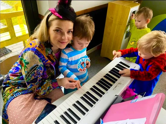 Zajęcia umuzykalniające — dzieci grają na pianinie z opiekunką
