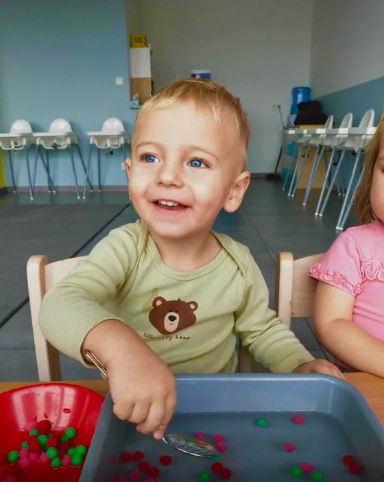 Uśmiechnięte dziecko podczas zabawy sensorycznej przy stoliku